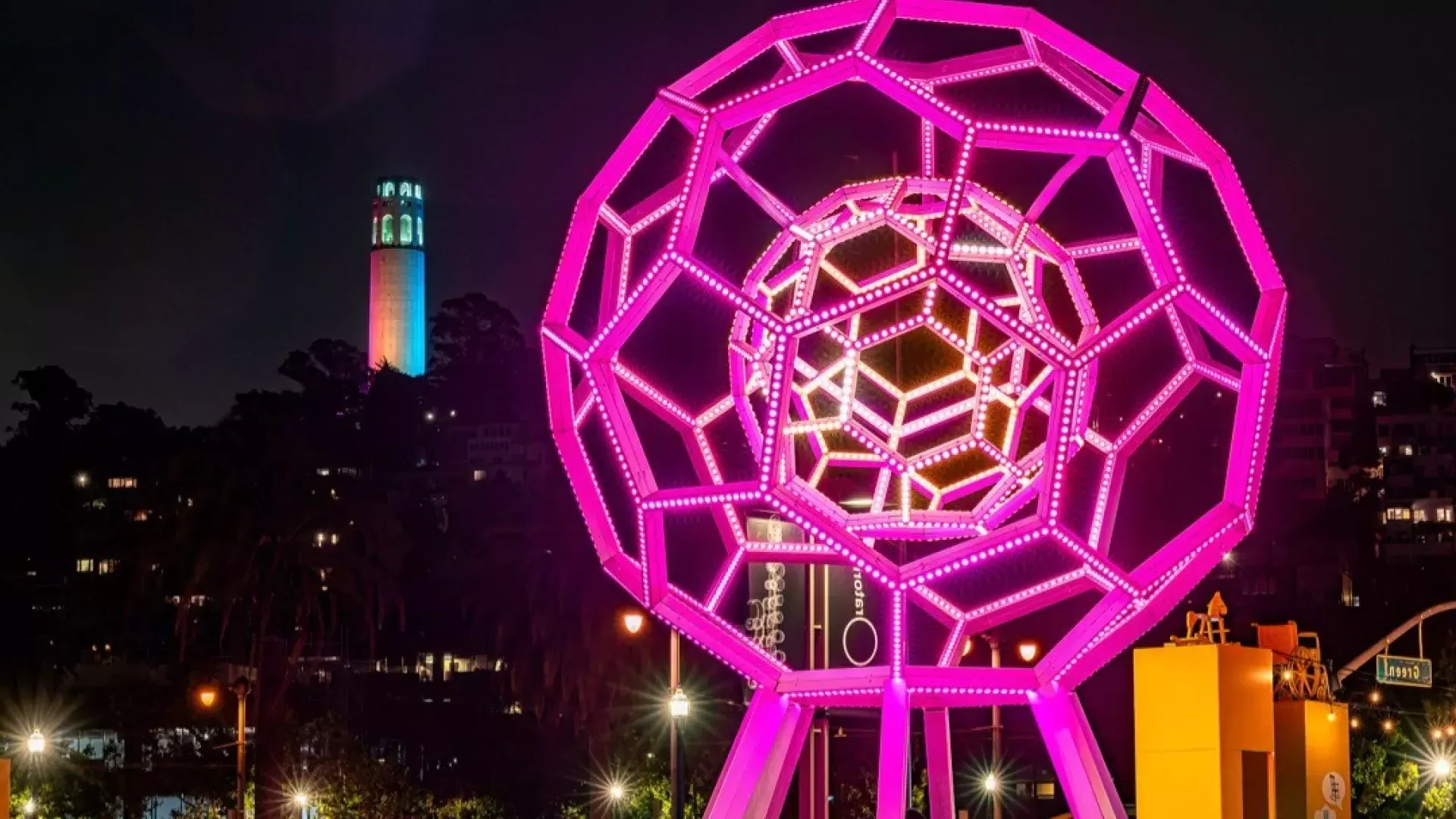 Buckyball leuchtet im Vordergrund, während Coit Tower in der Ferne erstrahlt.